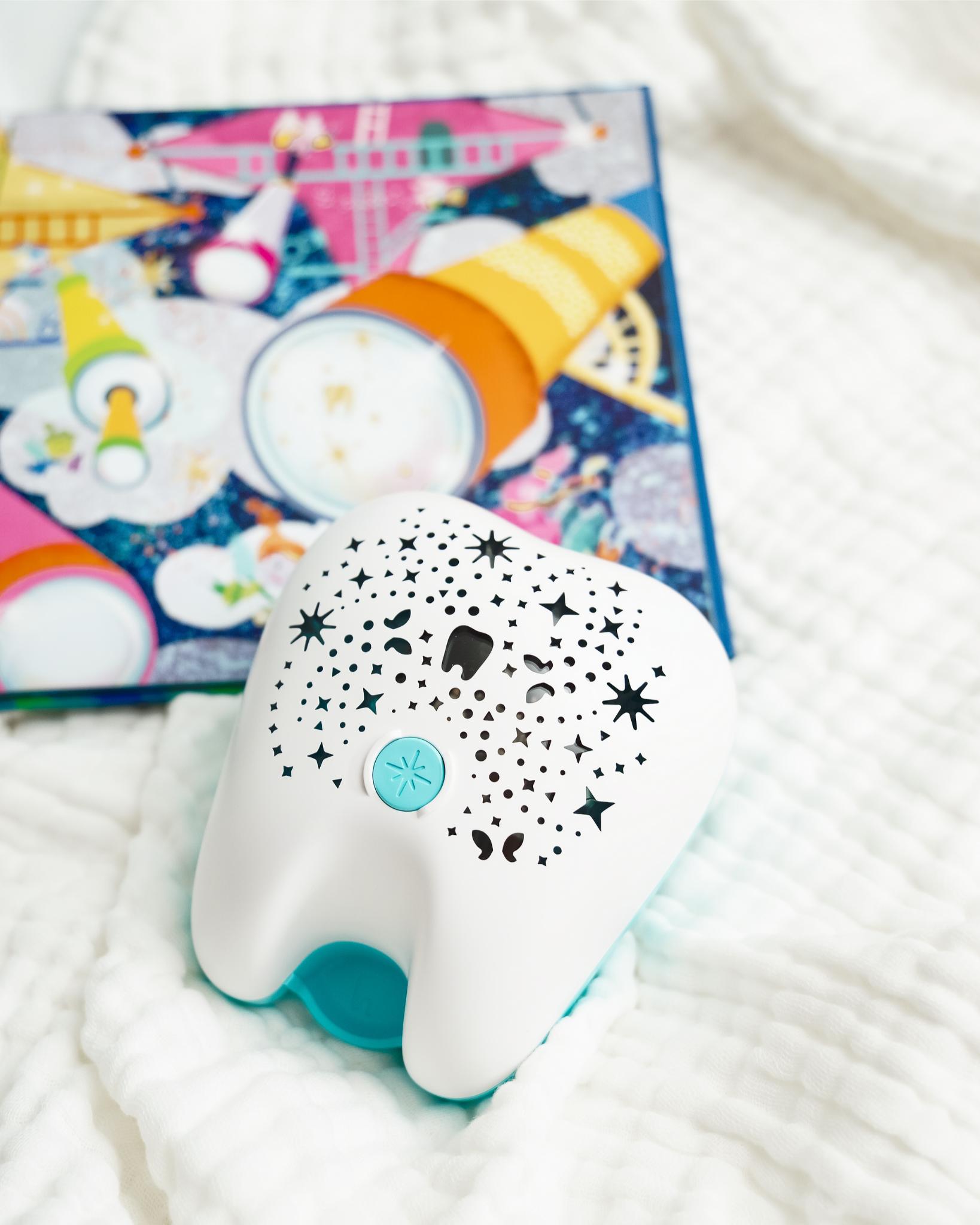 Tooth Fairy Flylight Nightlight Projector with Storybook on bed